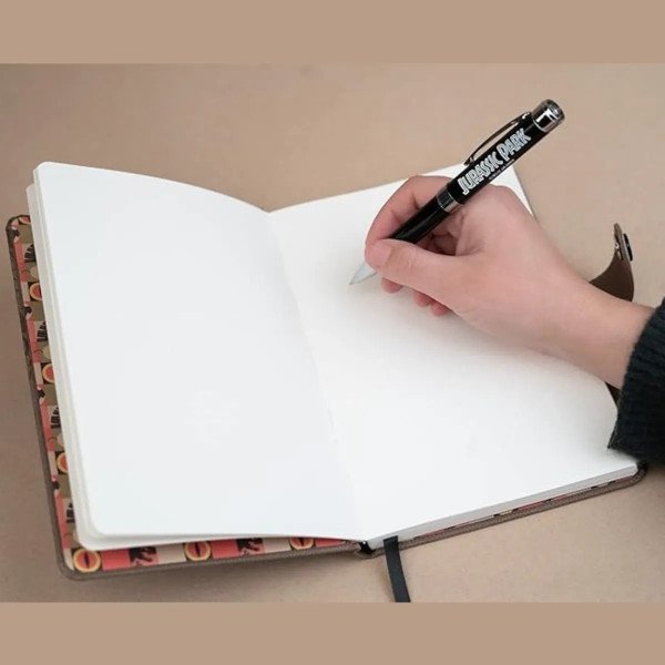 Carnet premium A5 Jurassic Park ouvert avec stylo projecteur utilisé pour écrire.