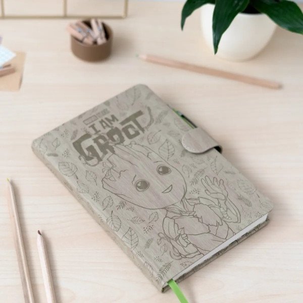 Carnet premium A5 Marvel Groot posé sur bureau, couverture illustrée effet bois et fermeture aimantée.