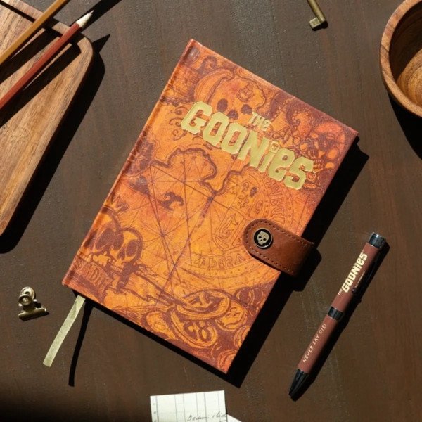 Carnet premium A5 Les Goonies carte au trésor posé sur un bureau avec stylo projecteur.
