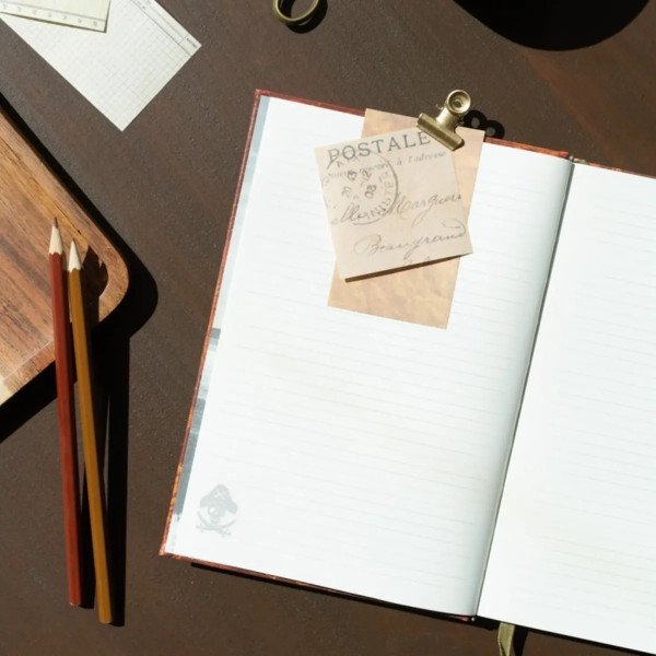 Carnet Les Goonies ouvert sur une page lignée avec accessoires de bureau style aventure.