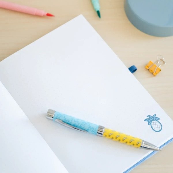 Détail d’une page du carnet premium A5 Disney Stitch Tropical avec le stylo projecteur posé dessus.