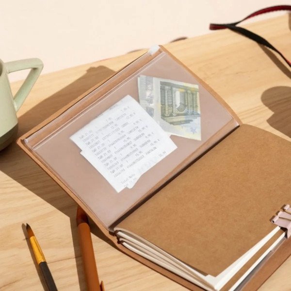 Intérieur du carnet de voyage Jurassic Park avec pochettes transparentes pour ranger tickets et souvenirs.