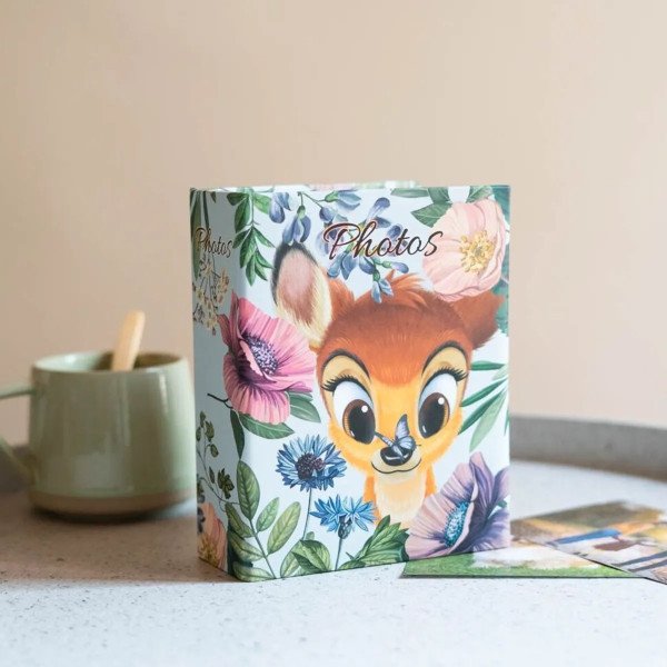 Album photo Bambi 100 pochettes 10x15 cm posé sur un plan de travail avec couverture fleurie
