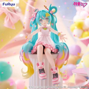 Figurine Hatsune Miku 10th Anniversary assise de face, robe rose et longues couettes turquoise dégradées