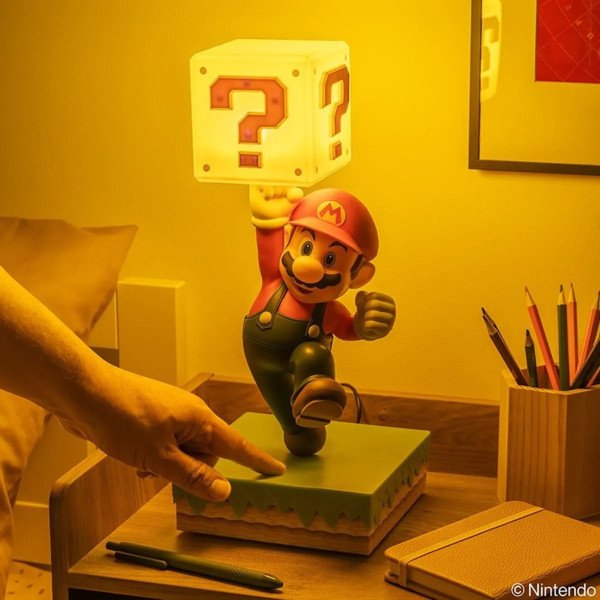 Lampe diorama Super Mario allumée, avec Mario tenant un bloc ? et une main activant la base.